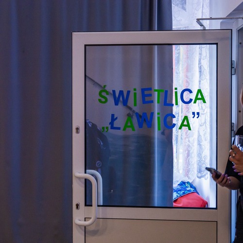 Dwoje ludzi stoją obok szklanych drzwi wejściowych z napisem 