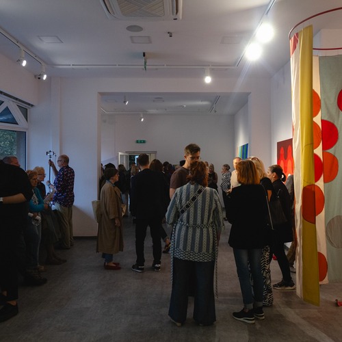 Tłum zwiedzających podczas wernisażu poruszający się po galerii.