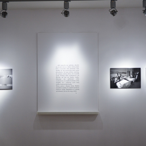 Ściana galerii z trzema czarno-białymi fotografiami szpitalnymi i poruszającym cytatem pośrodku.