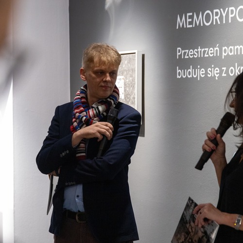 Autor wystawy wraz z kuratorką podczas otwarcia wystawy „MEMORYPOLIS” na tle ściany z opisem ekspozycji.