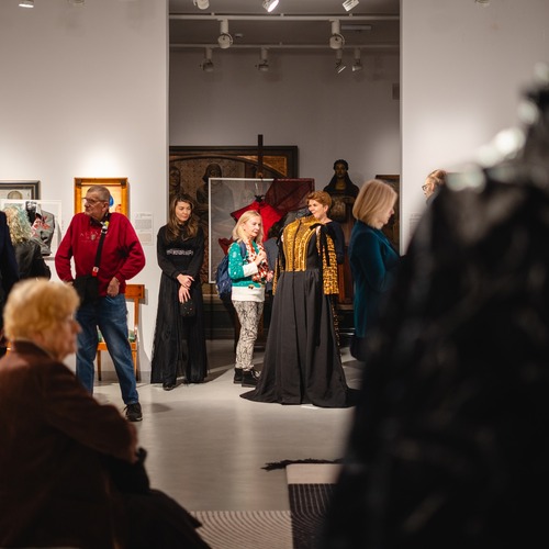 Grupa osób zwiedzających wystawę w galerii sztuki, oglądająca wystawę.